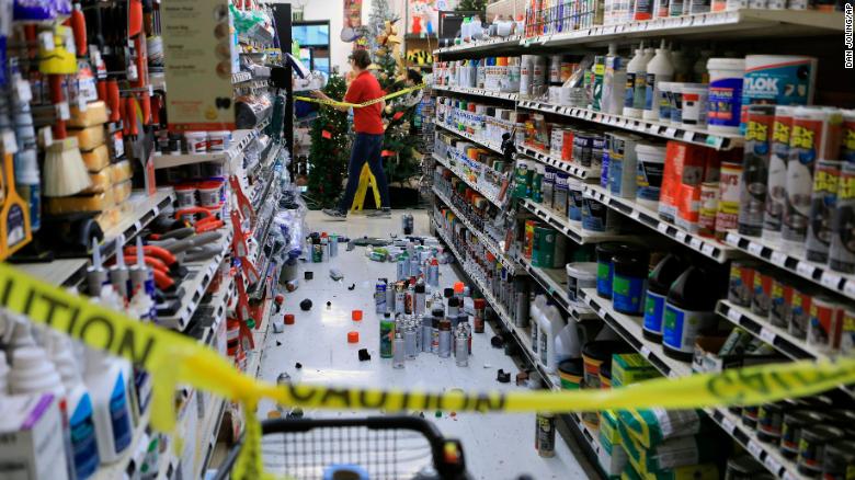 An employee walks past a damaged aisle at an Anchorage True Value hardware store.  