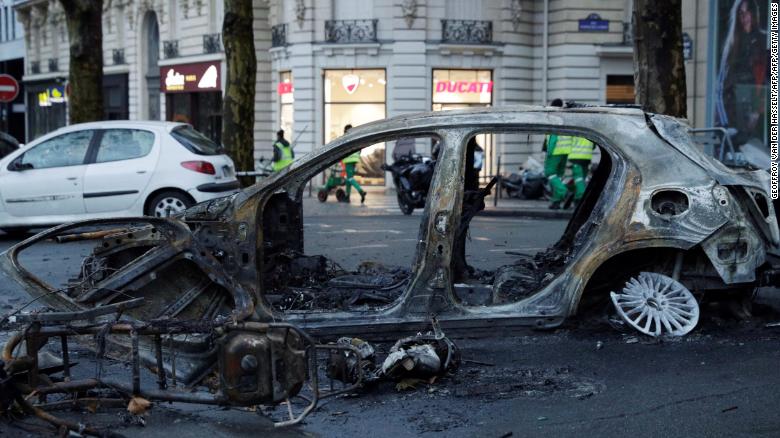 A burned-out car sits in a Paris street the day after riots spread through the city.