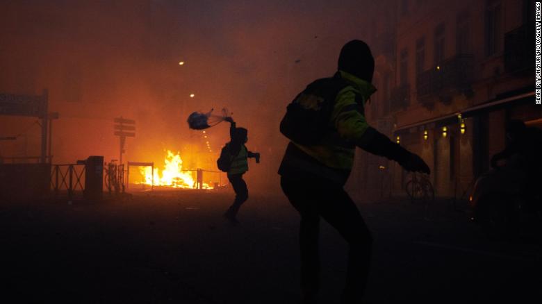 Protesters throw objects at riot police during a demonstration that turned violent when protestors clashed with police in Paris on Saturday, December 1.