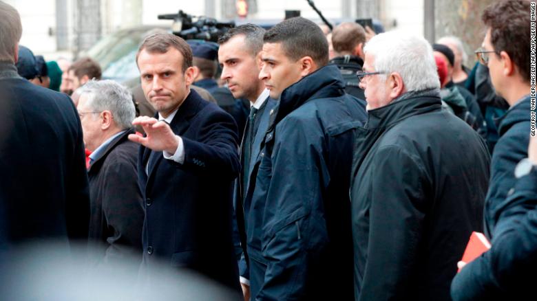 French President Emmanuel Macron waves as he leaves the Cafe Belloy, near the Arc de Triomphe in Paris on Sunday.