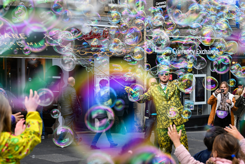 5月27日,在英国爱丁堡,街头艺术家吹出大量彩色泡泡逗乐儿童.