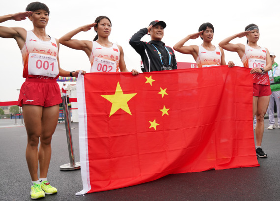 10月23日，中国队成员在女子个人全能越野跑比赛后手持国旗敬礼。新华社 图