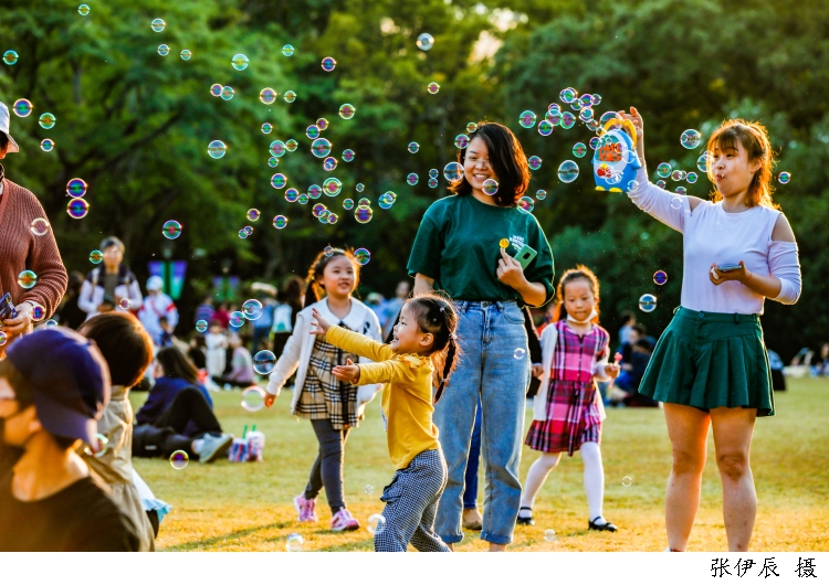 中山公园的肖邦音乐广场上满是前来享受秋高气爽的市民游客，游客正在用泡泡枪与孩子玩耍。.jpg