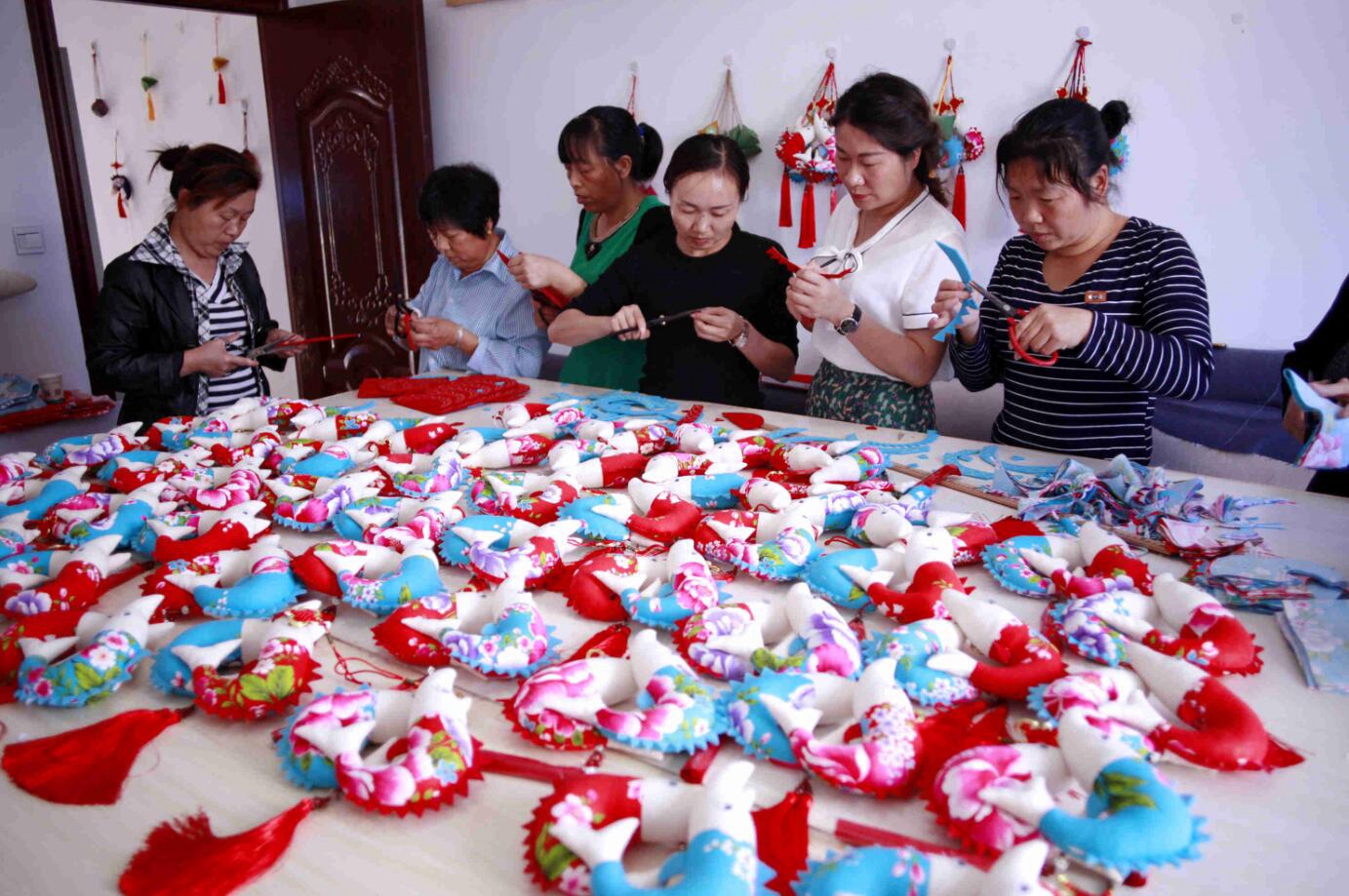 湖北夷陵，谢蓉（右二）带领合作社的妇女姐妹将艾草、中华鲟等地方元素加入特色非遗“牵花绣”中，制作手工艺品。.jpg