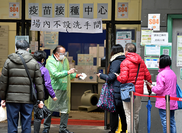 2月22日，在香港佐敦疫苗接种中心站，市民佩戴口罩排队接种疫苗。新华社 图