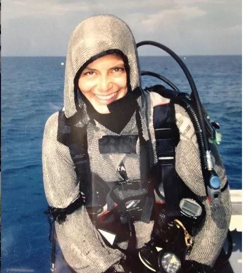 在加勒比海巴哈马群岛附近的一个美丽的海湾,一名女士穿上潜水服,然后