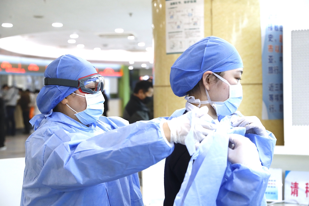 上海市第十人民医院预检分诊部的医务人员在结束了一天劳累忙碌的工作准备下班,同班的两位医务人员相互帮助脱下隔离衣。摄影 袁婧.jpg 上海市第十人民医院预检分诊部的医务人员在结束了一天劳累忙碌的工作准备下班,同班的两位医务人员相互帮助脱下隔离衣。摄影 袁婧.jpg