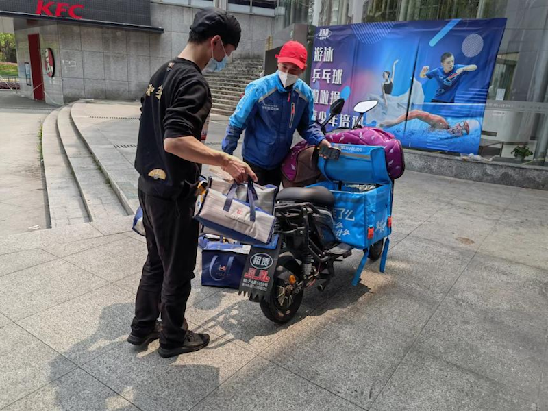 和府捞面的工作人员帮骑手将餐品放进外卖箱.png